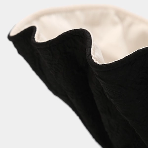 Dettaglio del tessuto trapuntato nero del cappello da sole con fodera beige