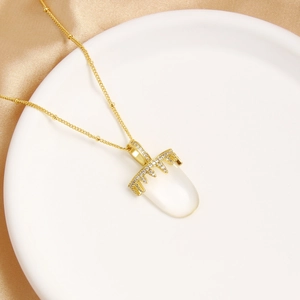 Detail of gold crown necklace with white oval gemstone on white silk background