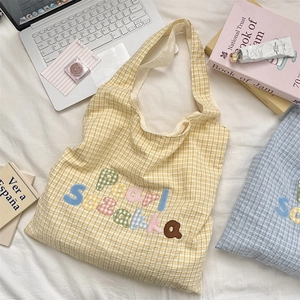 Detail of yellow plaid tote bag with colorful Pearl Suzakka embroidery and casual props