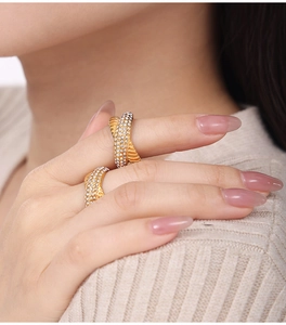 Detailed close-up of golden crossover rings with sparkling rhinestones on hand