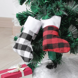 Classic plaid Christmas stockings in black, white, and red hanging on a festive tree