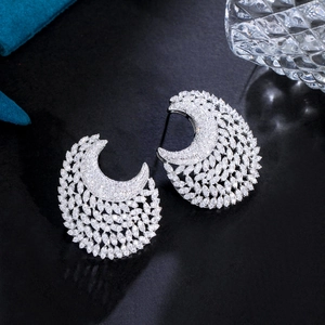 Detailed view of silver crescent earrings with sparkling cubic zirconia on blue velvet