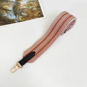 Detail of colorful geometric woven bag strap with black leather ends and gold metal hooks