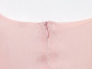 Détail du tissu perlé rose avec une fermeture éclair invisible assortie sur la robe
