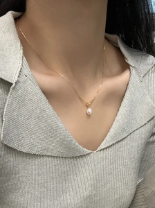 Close-up of a s925 silver gold-plated knot necklace with a white teardrop pearl pendant