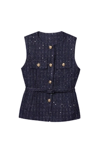Detail of dark blue sequin tweed vest featuring ornate golden spiral relief buttons