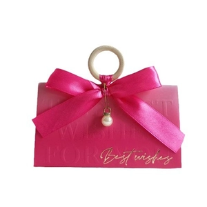 Detailed view of pink gift box featuring a wooden ring handle and gold Best Wishes text