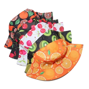 Dettaglio di cappelli a secchiello in cotone con motivi di ciliegie, arance e kiwi