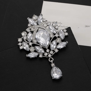 Macro detail of silver crown brooch with pear-cut crystals on black textured gift box