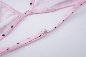 Detail view of adjustable pink polka dot bikini strap with metal buckles and connectors
