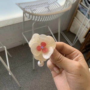 Macro shot of acetic acid flower hair clip with pink center and elegant pearl pendant