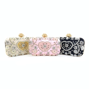 Three luxury beaded evening clutches in gold, pink, and black with floral crystal clasps