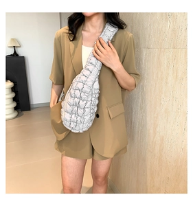 Sac bandoulière nuage argenté au design plissé matelassé porté avec un costume beige