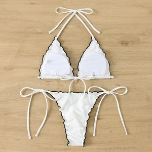Detailed view of white halter bikini with black scalloped edges on wood background