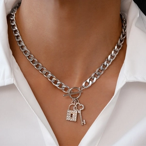 Close-up of silver Cuban chain necklace with rhinestone lock and key pendant on model