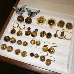 Collection of retro gold earrings with faux tiger eye stones in a velvet display box