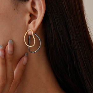 Close-up of minimalist gold and silver teardrop earrings worn by a model in detail