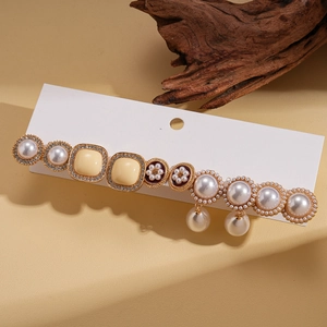 Detailed close-up of 10-piece earring set with pearls and rhinestones on wood display