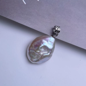 Macro shot of baroque pearl pendant with iridescent luster and silver hollow geometric clasp