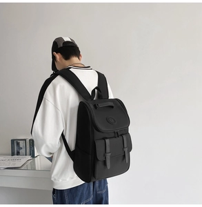 Back view of a black minimalist backpack featuring flap cover and buckle closure