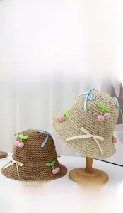 Detail of hand-woven straw hats featuring crochet cherries and elegant silk bow decorations
