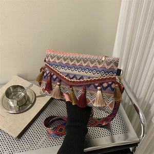 Detail of bohemian woven bag featuring colorful ethnic patterns and long tiered tassels