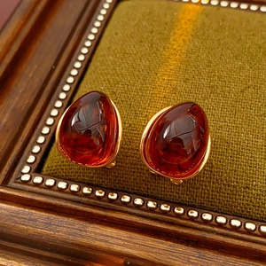 Macro shot of amber resin earrings with gold metal base on dark green velvet display