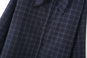 Dettaglio della trama della camicia a quadri blu navy e della chiusura a bottoni