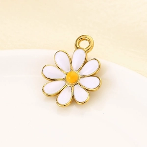 Detail of a golden daisy pendant with white petals on a white plate for DIY jewelry