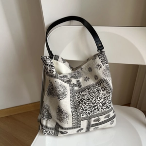 Detail of vintage linen tote bag with black floral patterns and sturdy leather straps
