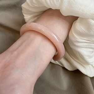 Close-up of a pink resin bangle with translucent texture on a model's wrist