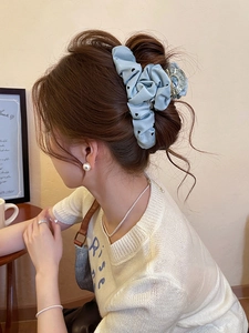 Detail of light blue polka dot hair scrunchie and transparent claw clip on bun