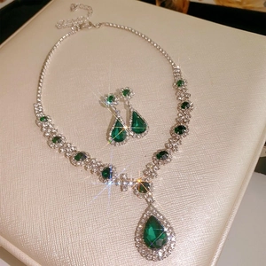 Detail of emerald teardrop jewelry set with sparkling rhinestones on beige leather