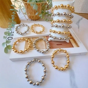 Elegant gold and silver beaded stretch bracelets on a white marble display setting