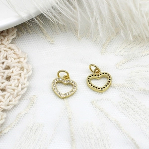 Detailed macro view of two gold heart pendants with micro-pave crystals on white lace