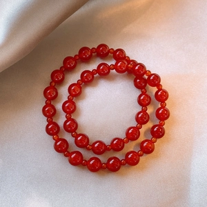 Vintage red agate beaded bracelet set on champagne silk fabric in a minimalist circular arrangement