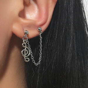 Close-up of silver tassel earrings with G-clef musical note pendant and delicate chain