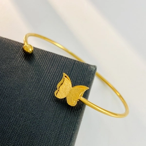Elegant gold open butterfly bracelet with matte textured wings on a dark jewelry box