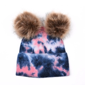 Détail du bonnet en maille tie-dye avec deux pompons en fourrure synthétique douce