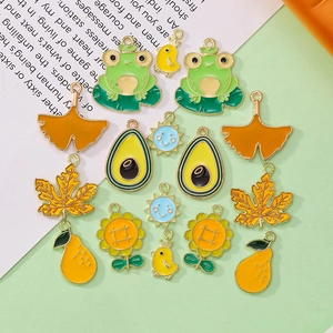 Detailed flat lay of colorful enamel charms featuring frogs, avocados, and sun pendants