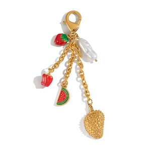 Détail de breloques fraise et pastèque dorées avec une perle baroque sur une chaîne