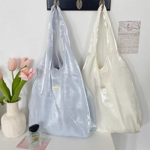 Detail of satin tote bags in pearl blue and cream white with high gloss finish