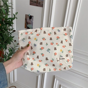 Detailed macro view of a floral bear pattern cotton makeup pouch held by a hand