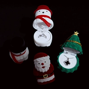 Detail view of festive velvet jewelry boxes featuring snowman and Santa Claus designs