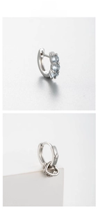Detail showing silver hoop earrings with blue zircon stones and dangling heart pendant