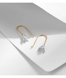 Detailed view of silver magnolia flower earrings with gold hooks on white background