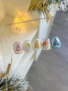 Détail des stickers ongles 3D de Noël avec sapins en résine et nœuds dorés élégants