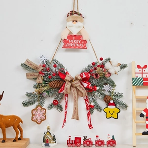 Detail of Christmas wreath with pine needles, red berries, and Santa Claus hanging ornament