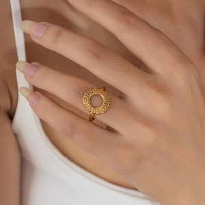 Detailed close-up of a hollow sunburst gear ring in 18K gold finish on a model hand