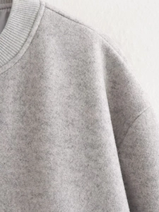 Détail macro du tissu polaire gris avec col côtelé et coutures d'épaule précises